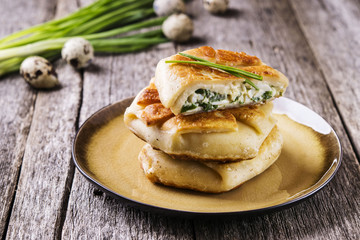 Patties with green onion, cottage cheese and egg filling on rustic wooden table. Fresh home baking. Selective focus 