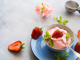 Home made strawberry ice cream in bowl with min leaves