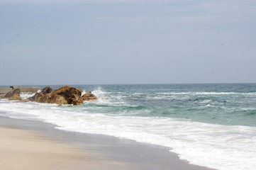 The sea, the blue aod, the waves are rooted about the stones. Summer, beach
