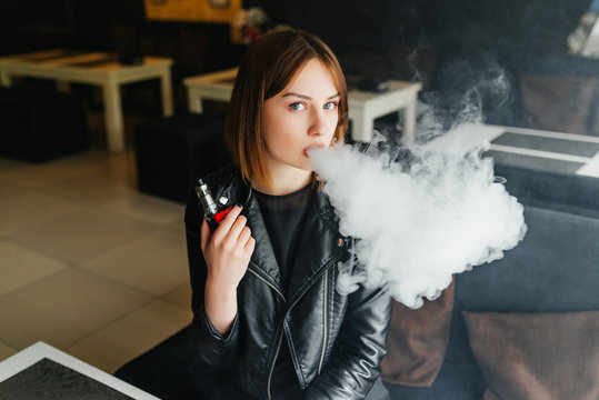 Beautiful blond girl produce smoke. Sensual Young Girl Vaping. A cloud of vapor.