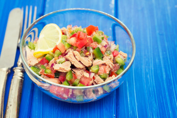 tuna salad with tomato and pepper in bowl on blue background
