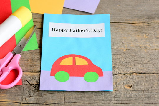Happy Father's day card. Colored paper sheets, scissors, glue on vintage wooden background. Father's day gift children can make for dad. Children paper greeting card crafts. Closeup
