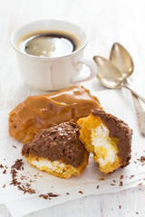 chocolated eclairs on white dish on wooden background