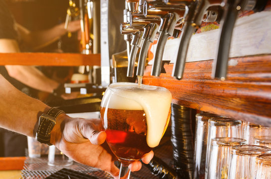 Bartender Hand Pouring Draught Beer To Glass From A Pub Tap