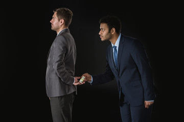 businessman giving money and bribing business partner isolated on black
