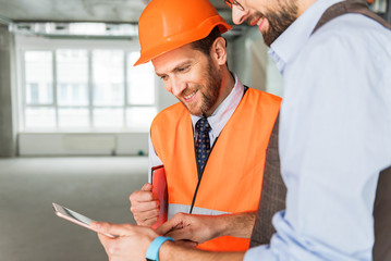 Hilarious smiling builders keeping gadget