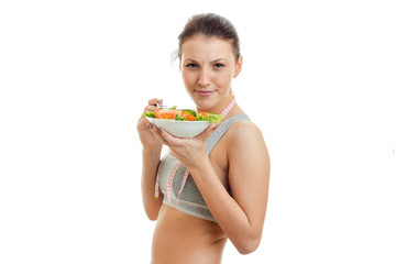 cheerful young brunette sports girl eats salad