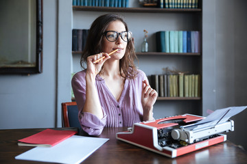 Portrait of a pensive mature authoress in glasses sitting