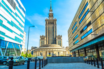 Fototapeta premium Pałac kultury i nauki w Warszawie w słoneczny dzień z błękitnego nieba i zielonych drzew.