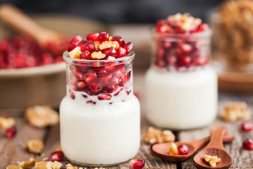 Fresh yogurt with pomegranate seeds and walnut in a glass jars
