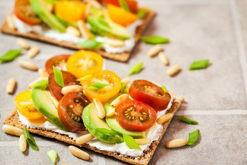 Сrisp bread toast  with cream cheese, fresh avocado, cherry tomatoes and pine nuts