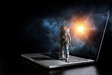 Space explorer and laptop. Mixed media - obrazy, fototapety, plakaty
