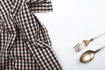 Background of plaid kitchen tablecloth and cutlery on white background. Copy space. Horizontal shoot.