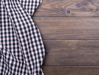 Background of plaid kitchen tablecloth on wooden background. Copy space. Concept.