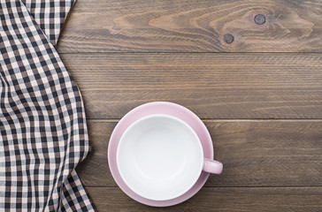 Background of checkered napkin next to ceramic ware on wooden background. Copy space.