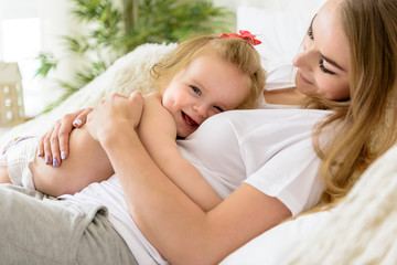 Obraz na płótnie Canvas Loving toddler hugging her parent on bed