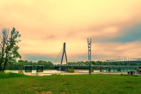 Modern bridge in Warsaw across the river next to a football stadium in the evening with a setting sun