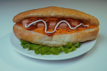 A delicious hot dog with a Korean carrot and spices on a salad leaf. Fast food