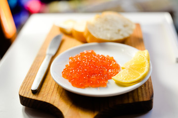 Closeup on person eating red caviar delicacy from white plate, closeup light macro background