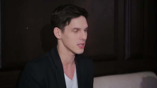 Young attractive charismatic guy sitting on the couch actively gesturing during conversation