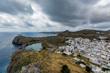 Fototapeta na wymiar Cityscape of Lindos and view of St Paul's Bay on a cloudy day, view from the Lindos castle, Rhodes island, Greece