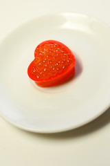 Closeup on love heart shape red caviar delicacy on white plate, closeup light macro background