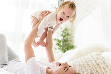 Obraz na płótnie Canvas Excited toddler having fun with her mom