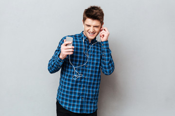 Young student enjoying music in headphones on smartphone
