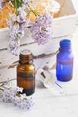 Fototapeta na wymiar Bottle of essential oil with fresh lilac flower