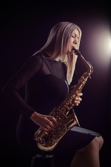 Obraz na płótnie Canvas Female jazz musician sitting on chair and playing saxophone