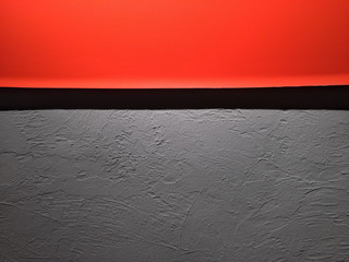 Minimalist delicious 04
Bright orange poster with black design detail over a grey plastered background wall.