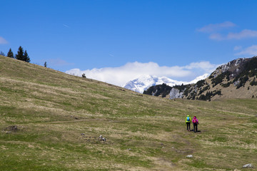 Fototapeta na wymiar Hikers walking on hike in mountain nature landscape in Slovenian Alps. Hiking – sporty hiker woman on trek with backpack living healthy active lifestyle