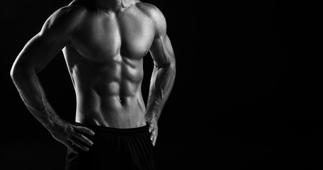 The torso of attractive male body builder on black background. - obrazy, fototapety, plakaty