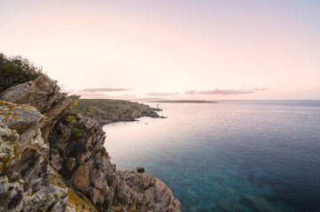 Seascape of the Italian coast at sunset with a lighthouse in the background. Porto Cervo - Emerald...