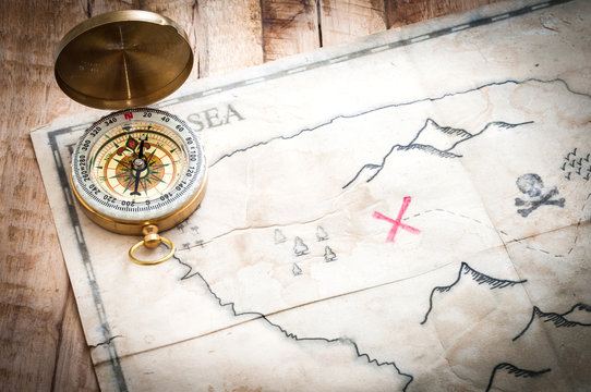 Vintage compass and treasure map on wooden table with vignette effect