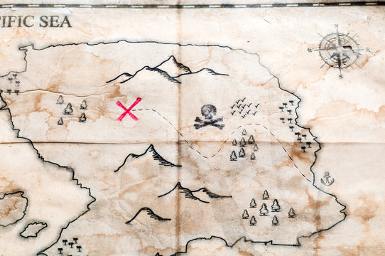 Close up to Vintage folded fake map with red cross of Pirates Treasure chest