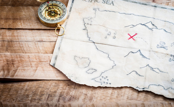 Treasure map of abstract island with Compass on plank wooden table