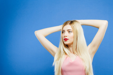 Portrait of Sensual Blonde with Red Lips on Blue Background. Cute Girl is Posing in Studio.