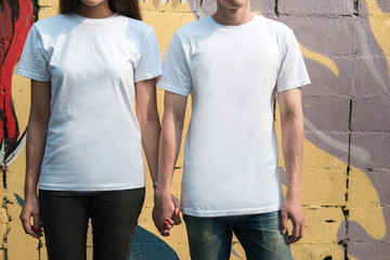 Young man and girl in white T-shirts standing on the street