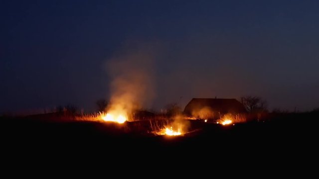 Conflagration on the farmers field at night. Fire inferno rural scene.