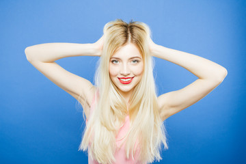 Portrait of Smiling Blonde Wearing Pink Dress on Blue Background. Amazing Pretty Woman with Long Hair is Having Fun Posing in Studio.