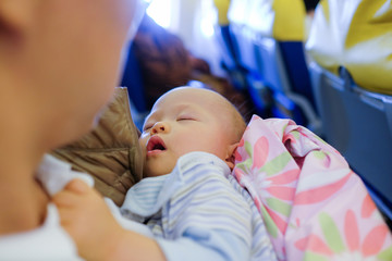 Adorable Baby Sleeping On Airplane ,Toddler boy sleeping on father's laps while traveling in airplane,Flying with children. Dad and sleeping 10 months old baby, Dad holding son:Shallow depth of field