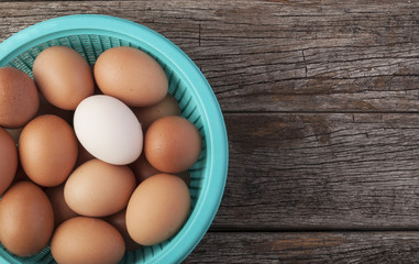 One white egg among eggs in a basket egg - Top view