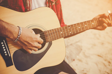 Young man playing the guitar on the beach.