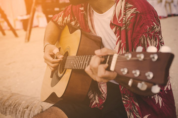 Young man playing the guitar on the beach.