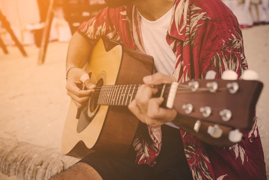 Young Man Playing The Guitar On The Beach.