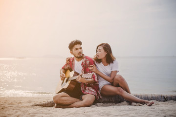 Young couples playing guitar and singing on the beach.