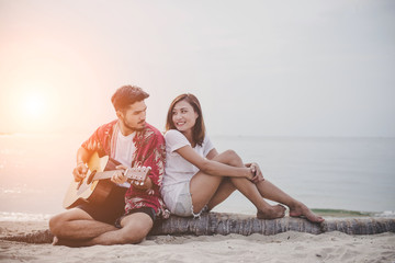 Young couples playing guitar and singing on the beach.