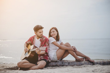 Young couples playing guitar and singing on the beach.