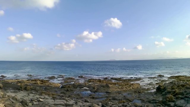Timelapse of the ocean and clouds on a rocky shore in Lanzarote, a ship in the background, Canary islands, Spain - Video HD